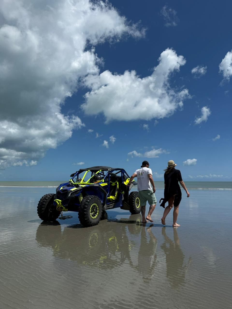 Casal caminhando ao lado do UTV na praia